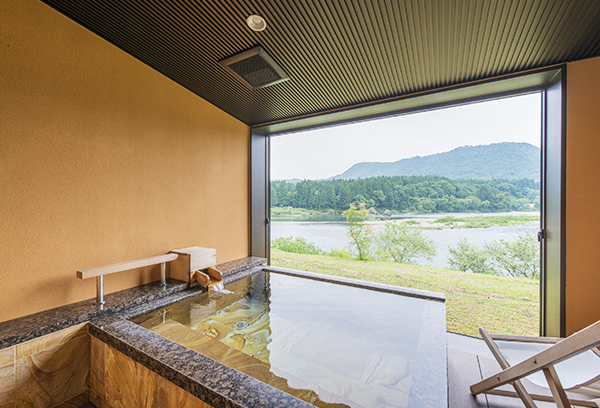 露天風呂付き客室「せせらぎ」の格調漂う天然石の露天風呂と阿賀野川の眺望。贅沢な空間です。